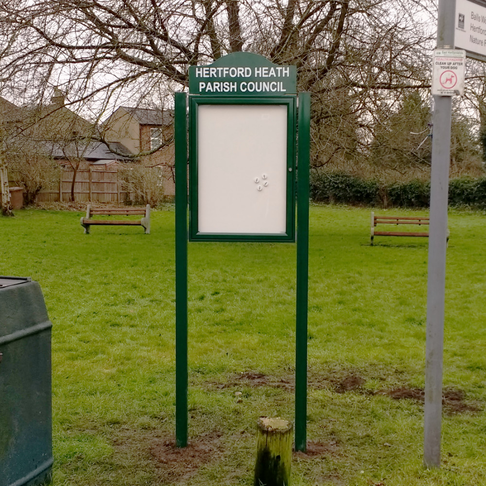 Small green notice board with header and posts set in a park
