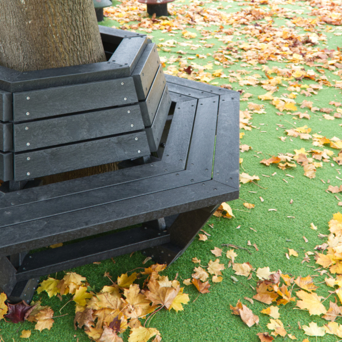 Recycled plastic tree seat in black on Astroturf around a large tree