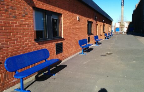 Blue steel seats lined up against a red brick building