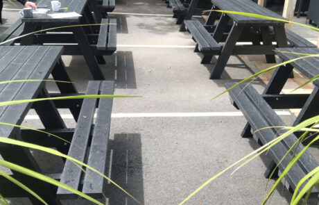 Two rows of black picnic tables in an outdoor setting