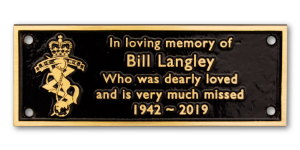 Cast bronze memorial plaque with black background and gold lettering and emblem