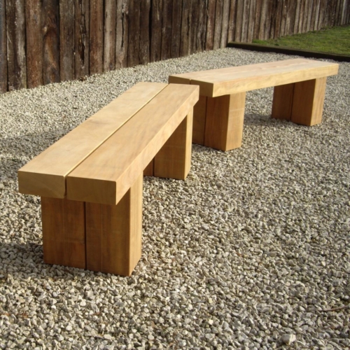 Two simple chunky oak benches set in gravel