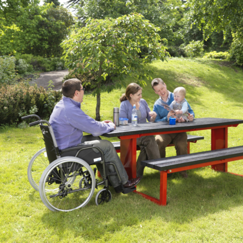 Red and black mobility picnic table set on grass with people sitting at it