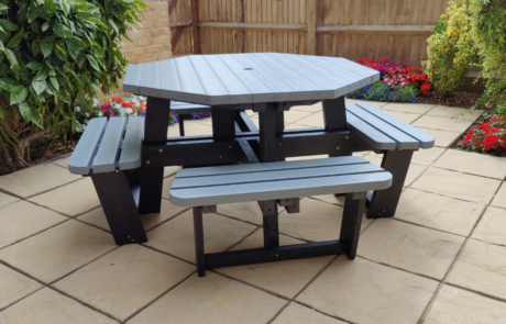 Grey and black recycled plastic picnic table on garden paving slabs