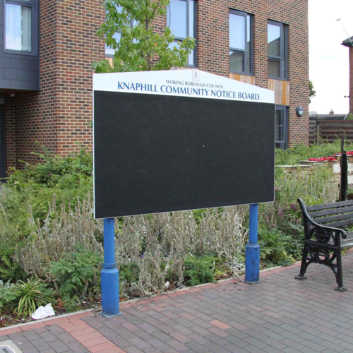 Large community notice board with black pinnable surface, blue legs and white header