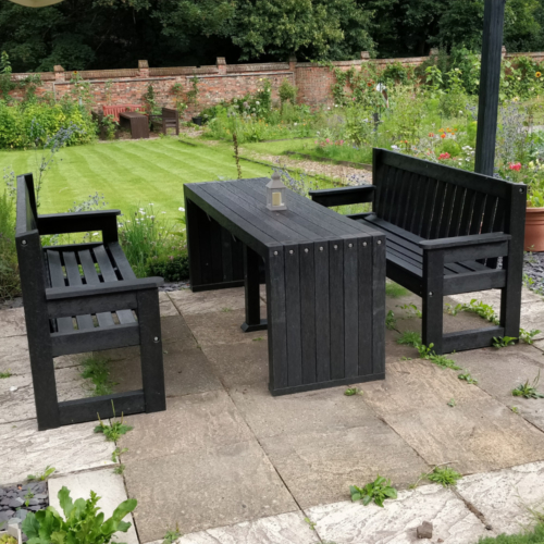 Black recycled plastic outdoor bench and seats in a garden setting