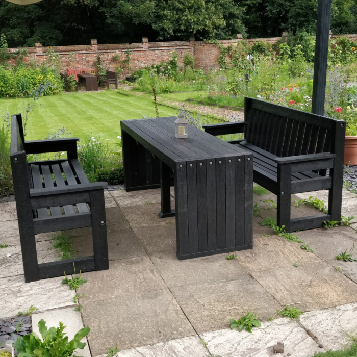 Black recycled plastic outdoor bench and seats in a garden setting