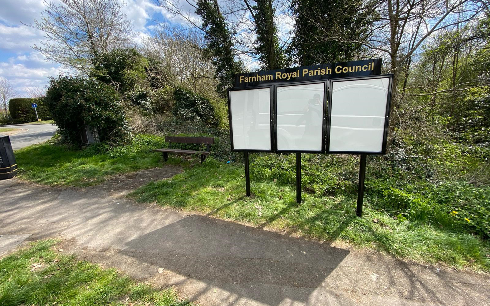 Three door notice board with posts on a grass verge