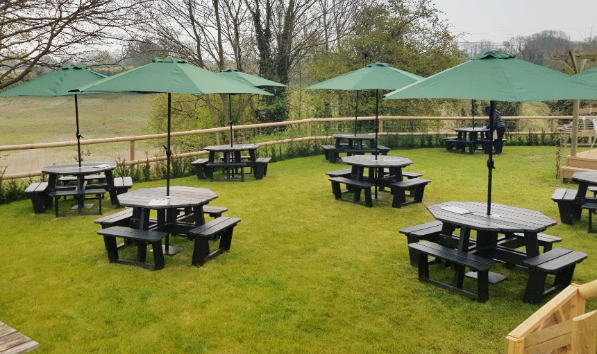 Black octagonal recycled plastic picnic benches in tea garden