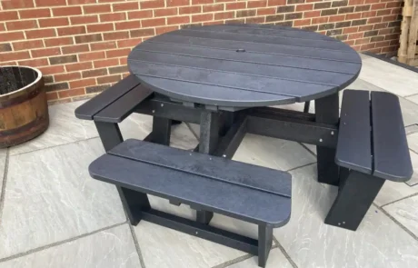 Robert-Potts-Round-Picnic-Table-in-Black Round black picnic table on paving slabs