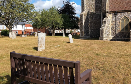 Surrey Seat at St Andrews Church Brown recycled plastic seat in front of a church in-between grave stones